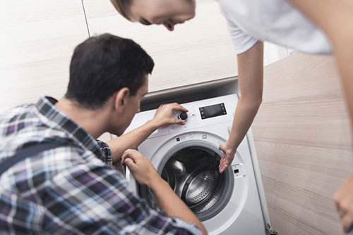 Person sitzt an einem Schreibtisch und hält einen Bauplan in der Hand. Daneben liegt das Modell eines Solarmoduls.